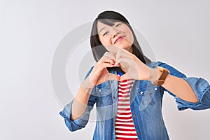Chinese woman wearing denim shirt and red striped t-shirt over isolated white background smiling in love showing heart symbol and
