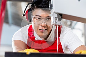 Chinese worker on saw in industrial factory