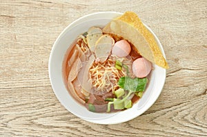 Chinese yellow egg noodles with fish ball and chop pork in red soup on bowl