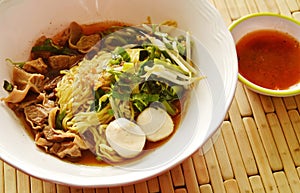 Chinese yellow noodle topping braised pork in brown soup and spicy chili sauce