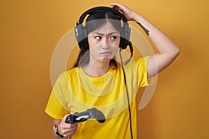 Chinese young woman playing video game holding controller confuse and wondering about question