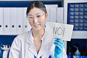 Chinese young woman working at scientist laboratory holding no banner looking positive and happy standing and smiling with a