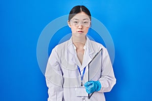 Chinese young woman working at scientist laboratory relaxed with serious expression on face