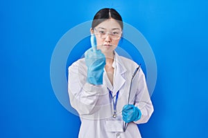 Chinese young woman working at scientist laboratory showing middle finger, impolite and rude fuck off expression