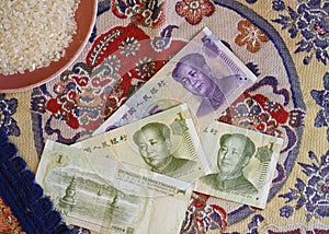 Chinese yuan banknotes and a cup of rice on the background of national embroidery