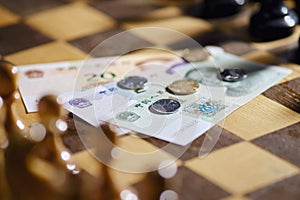 Chinese yuan money on the background of a chess board. Banknotes and coins of yuan from China on chessboard