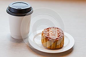 A Chiness moon cake with a hot disposable coffee cup