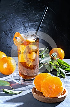 Chinotto drink in the glass with ice and fruits on the grey table photo