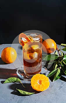 Chinotto drink in the glass with ice and fruits on the grey table photo