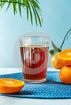 Chinotto refreshing citrus drink with fruits, palm branch on bleu background. Vertical banner with copy space photo