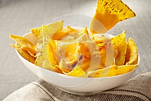 Chip pulled out of bowl of cheese covered nachos