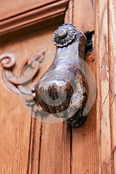 Chipped doorknocker with hand shape on wooden door