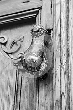 Chipped doorknocker with hand shape on wooden door