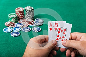 Chips and cards for poker in hand on green table