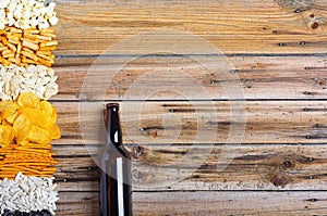 Chips, crackers, seeds, nuts and bottle of fresh cold beer on wooden table