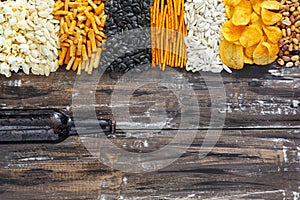 Chips, crackers, seeds, nuts and bottle of fresh cold beer on wooden table