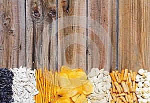 Chips, crackers, seeds, nuts on wooden table