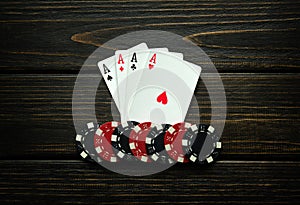 Chips and playing cards with a winning combination of four of a kind or quads on a black vintage table. Concept of winning in a