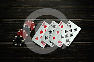 Chips and playing cards with a winning combination of four of a kind or quads on a dark vintage table. Concept of winning in a