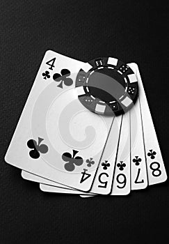 Chips and playing cards with a winning combination of straight flush. The concept of luck or fortune in a poker club. Black and