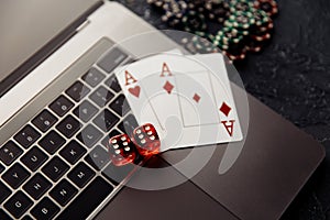 Chips, red dices and playing cards with aces for poker online or casino gambling on laptop keyboard top view. Online