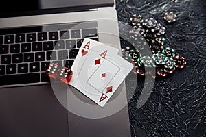 Chips, two red dices and playing cards with aces for poker online or casino gambling on laptop keyboard. Online casino
