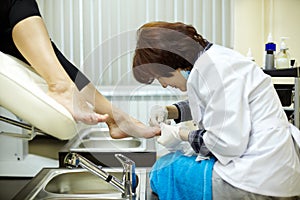 Chiropody master processes nails of client photo