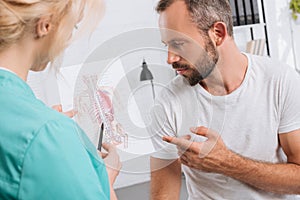 chiropractic showing human body picture to male patient during appointment