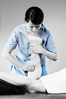 Chiropractor doing calf muscle massage to man patient in silhouette studio.