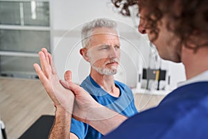 Chiropractor giving help to senior man with arm pain for physical recovery