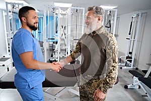 Chiropractor greets a man in military clothing at rehabilitation center