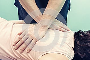 Chiropractor making treatment procedures. Young woman relaxing on massaging table, masseur working with her back. Beauty, health,