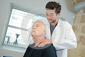 Chiropractor manipulating senior patient's neck