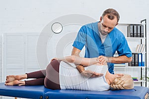 chiropractor massaging back of patient that lying on massage table