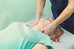 Chiropractor massaging neck of patient that lying on massage table in hospital