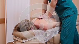 Chiropractor massaging a woman lying on a massage table, flexing the shoulder