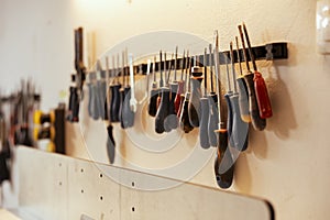 Chisels, screwdrivers, wrench and pliers on wall in carpentry studio