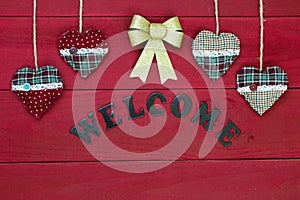 Chistmas welcome sign with red and green hearts and gold bow on wooden door