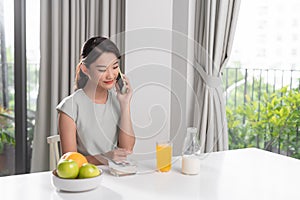 Chit-chat with her friends. Woman talking on her cellphone while having breakfast at her home