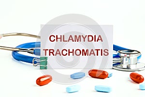 Chlamydia trachomatis on a white business card on a white background next to a stethoscope and pills, vitamins