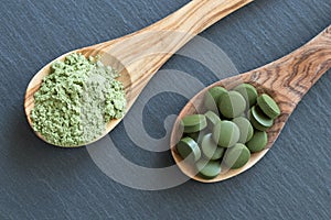 Chlorella and young barley powder on two wooden spoons