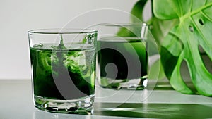 Chlorophyll extract is poured in pure water in glass against a white grey background with green leaf photo