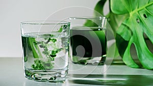 Chlorophyll extract is poured in pure water in glass against a white grey background with green leaf photo