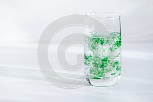 Chlorophyll in glass  on white wooden background. Copy space, sunlight