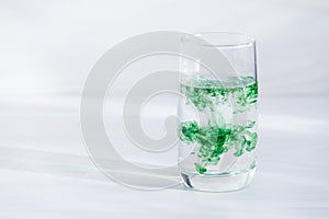 Chlorophyll in glass  on white wooden background. Copy space, sunlight