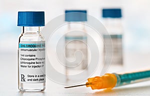 Chloroquine phosphate drug in small injection bottles with blue caps, orange green syringe near, closeup detail own label design