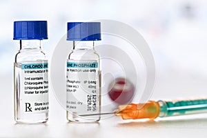 Chloroquine phosphate generic name drug in small injection bottles with blue caps, orange green syringe near own label design