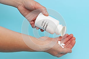 Chloroquine Phosphate - White plastic packaging bottle in the hands with tablets.  on blue background