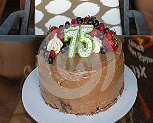 Chocloate birthday cake with 75th birthday candles and patriotic red, white and blue toppings.