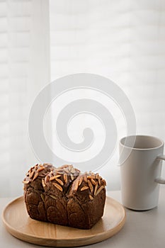 Chocolate almond bread loaf on wood dish and coffee mug